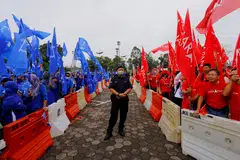 A police stands guard between supporters of The National Front coalition, Barisan Nasional, and The Alliance Of Hope, Pakatan Harapan, outside a nomination centre on nomination day in Bera, Pahang, Malaysia. 
