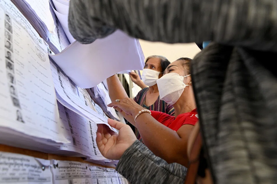 People looking for their names in the voters' list at a polling station as lines formed in polling stations amid heightened security before polls closed.
