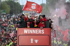 Liverpool's players wave at supporters from an open-top bus during a parade to celebrate their 2 trophies last season. The Reds battle Manchester City in the Community Shield on July 30, 2022. 