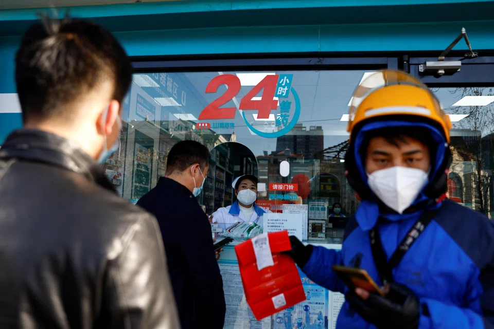 People line up to buy fever and cold medicine as a delivery worker picks up an order at a pharmacy, in Beijing, China, Dec 6, 2022. 