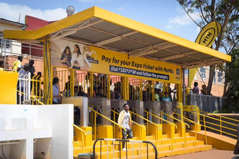 Customers stand in line to top up a mobile money account at designated yellow booths in Kigali, Rwanda. For those without a bank account, this is the only way to use a mobile money account.