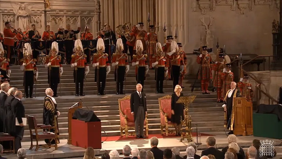 A grab from a handout video made available by the UK Parliamentary Recording Unit shows Britain's King Charles III (at centre left) and Camilla the Queen Consort and speaker of the House of Commons Lindsay Hoyle (right) singing the national anthem following his address to the Houses of Parliament at Westminster Hall in London. 