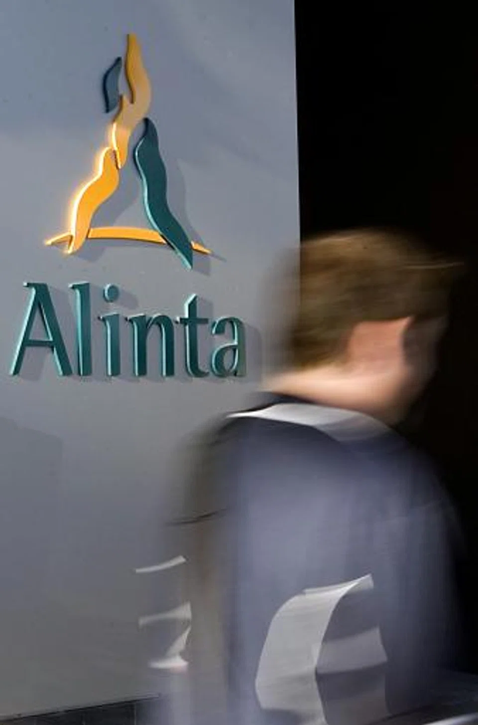  This file photo dated 02 April, 2007 shows a man walking past the headquarters building of Australian energy infrastructure group Alinta in Perth.  