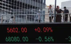 epa10811381 People walk on a pedestrian bridge with a screen showing stock exchange data, in Shanghai, China, 21 August 2023. Asian markets faced a setback on 21 August as China's reduction in lending rates proved to be smaller than anticipated. This extends Beijing's trend of providing stimulus measures that are more conservative than expected. The one-year loan prime rate (LPR) experienced a ten basis points reduction by the People's Bank of China, whereas the unchanged five-year rate, employed in calculating mortgage expenses, remained steady.  EPA-EFE/ALEX PLAVEVSKI