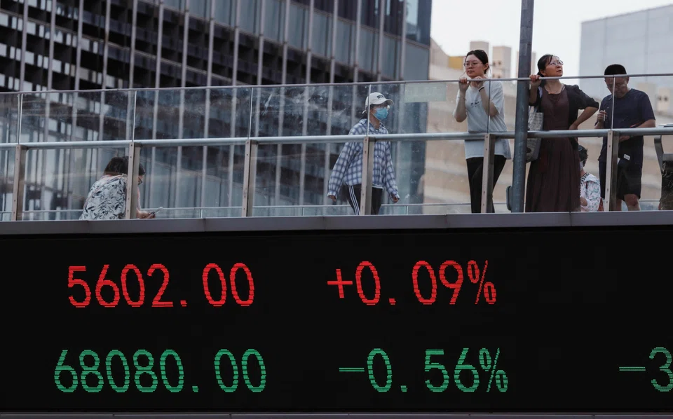 epa10811381 People walk on a pedestrian bridge with a screen showing stock exchange data, in Shanghai, China, 21 August 2023. Asian markets faced a setback on 21 August as China's reduction in lending rates proved to be smaller than anticipated. This extends Beijing's trend of providing stimulus measures that are more conservative than expected. The one-year loan prime rate (LPR) experienced a ten basis points reduction by the People's Bank of China, whereas the unchanged five-year rate, employed in calculating mortgage expenses, remained steady.  EPA-EFE/ALEX PLAVEVSKI