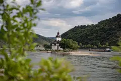 A cargo vessel sails along a single navigable channel on the River Rhine in Kaub, Germany. An extended dry spell in the area, which is on a key hard-coal import route, risks choking Germany's energy supply further, stoking power-price volatility and elevating costs for coal-heavy generators. 