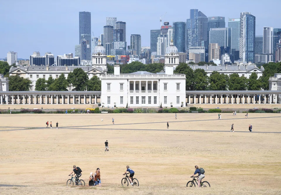 People walk on parched ground in Greenwich Park in London, Britain, Aug 6, 2022. A cascade of extreme weather exacerbated by climate change devastated communities across the globe this year, including sweltering heat and drought across Europe.