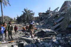 Palestinians walk across the rubble of a collapsed building following an Israeli airstrike in the Zuwayida district of central Gaza, Feb 22, 2024. 