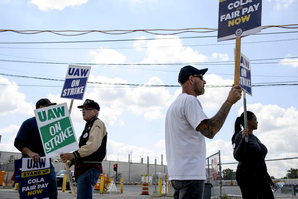 Members of the UAW pace the entrance gates while on strike outside the Ford Michigan Assembly Plant. Some 500 more workers were laid off by Ford and GM from the ongoing strikes.