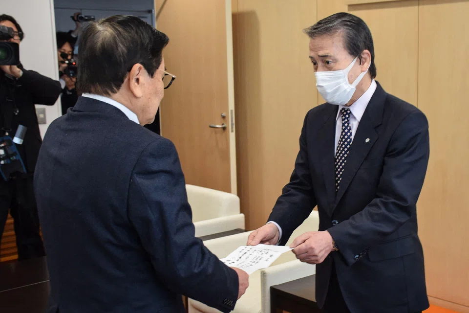 Japanese mayor Hideo Kojima (right) hands over his resignation to chairman Akira Sakurai (left) in the town of Ginan, Gifu prefecture after an official investigation accused Kojima of allegations of sexual harassment, Feb 29, 2024.