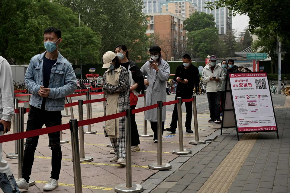 People queue to get a swab test for the Covid-19 coronavirus at a swab collection site in Beijing on May 10, 2022. 