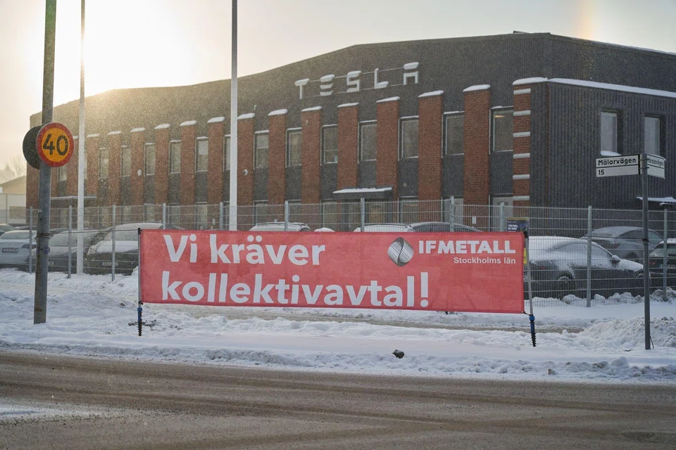 A banner reading "We demand a collective agreement" outside the Tesla service centre in Segeltorp, Sweden, on Dec 5. The labour row has spread to Denmark and Norway, where unions have warned they will block shipments of Tesla cars.
