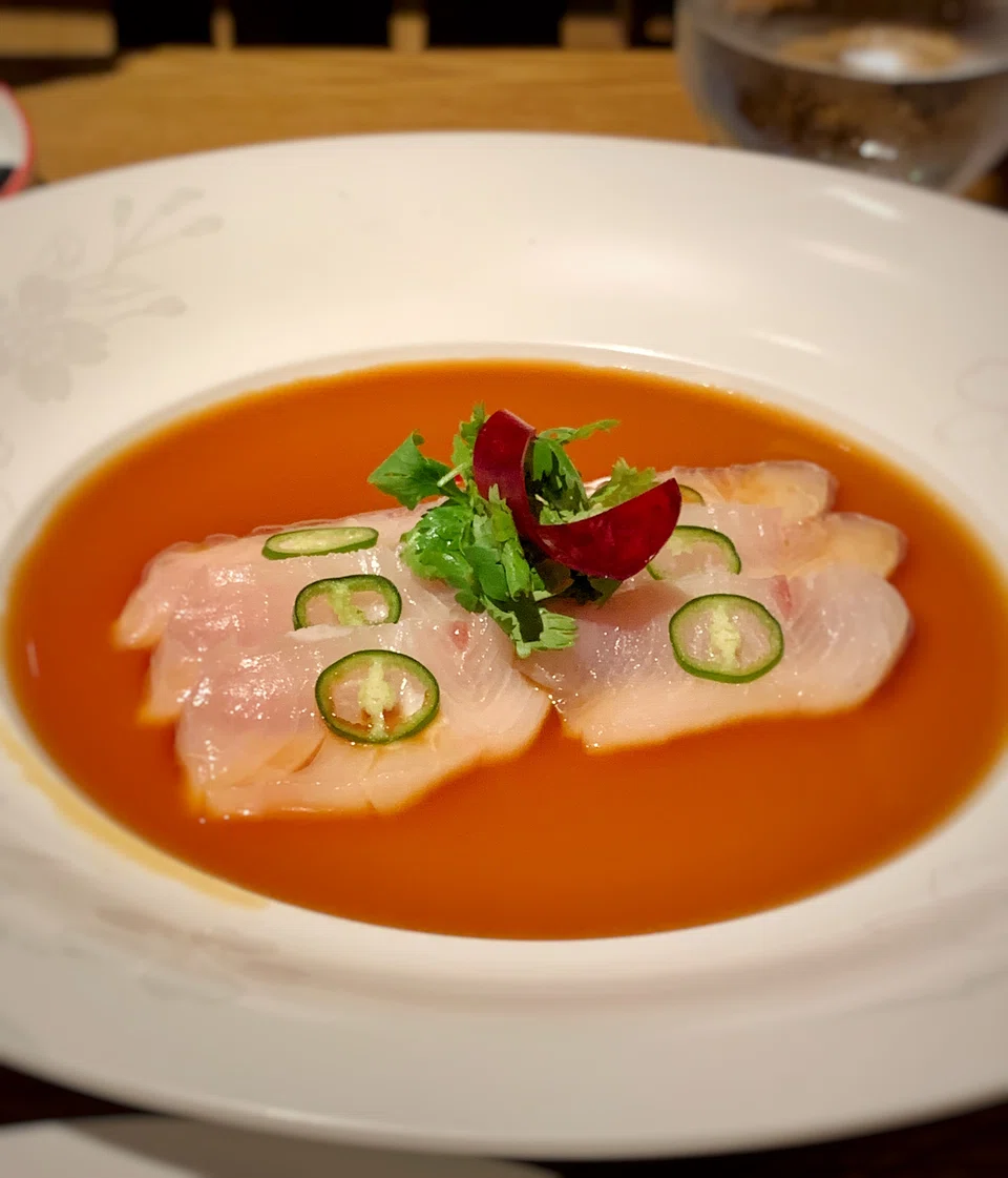 Yellowtail sashimi topped with green chilli in a ponzu-like sauce.