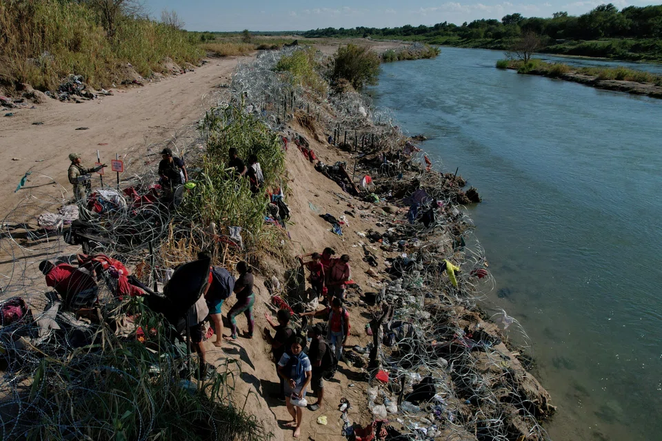 Members of the Texas National Guard try to dissuade migrants from climbing over the razor wire after they crossed the Rio Grande in Eagle Pass, Texas.