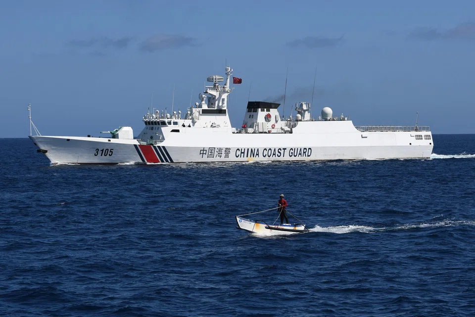 A Filipino fisherman (front) sailing past a Chinese coast guard ship near the China-controlled Scarborough Shoal, in disputed waters of the South China Sea, Feb 16, 2024. Maritime security - and China’s increasingly aggressive behaviour in the South China Sea - figures to be one of Asean's major focal points.