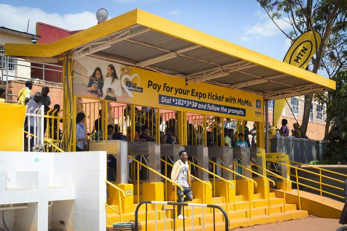 Customers queue up to top up a mobile money account at designated yellow booths in Kigali, Rwanda. For those without a bank account, this is the only way to use a mobile money account.