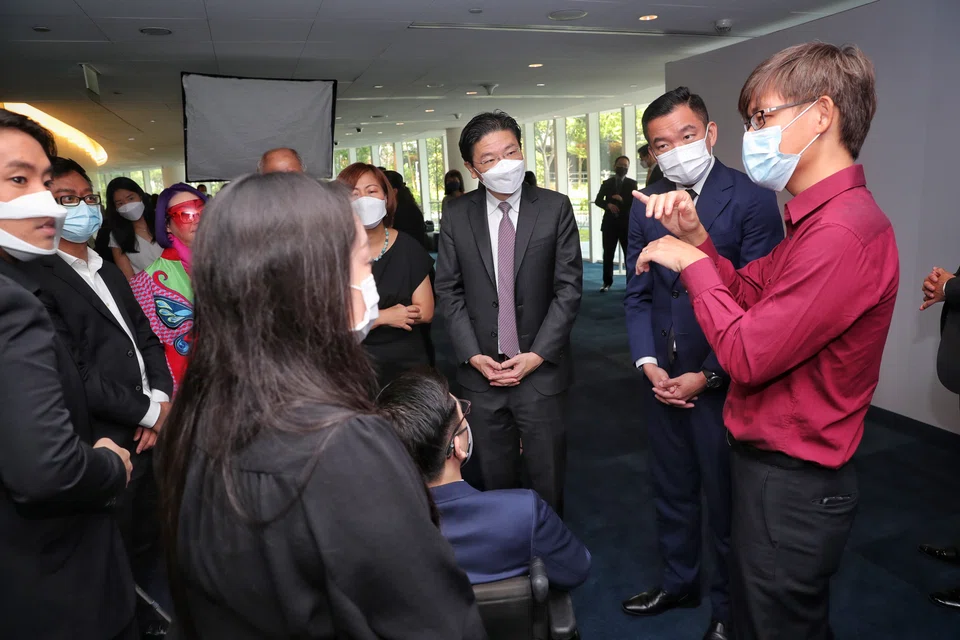 Yeong Zhi Wei (in red, and who is deaf), 34-year-old associate cybersecurity specialist with GovTech Singapore, communicating with Deputy Prime Minister Lawrence Wong and Senior Parliamentary Secretary for Culture, Community and Youth and for Social and Family Development Eric Chua through hand signs (translated by the lady in black on the left) at the Inclusive Business Forum.