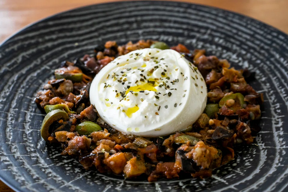 Burrata Siciliana features fresh creamy cheese surrounded by melting soft smoked eggplant
