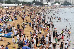 People cooling off on a beach in Qingdao, in China's eastern Shandong province on July 10, 2022. Many parts of China are experiencing scorching temperatures as a result of climate change, experts say.