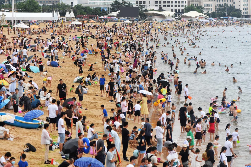 People cooling off on a beach in Qingdao, in China's eastern Shandong province on July 10, 2022. Many parts of China are experiencing scorching temperatures as a result of climate change, experts say.