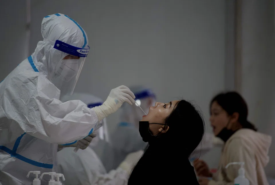 A health worker takes swab sample on a woman to be tested for Covid-19 coronavirus at a swab collection site along a street in Beijing on April 25, 2022.