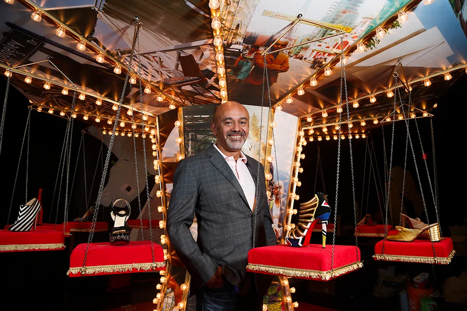 French shoe designer Christian Louboutin poses with some of his famous footwear while preparing for an exhibition of his work in Toronto.