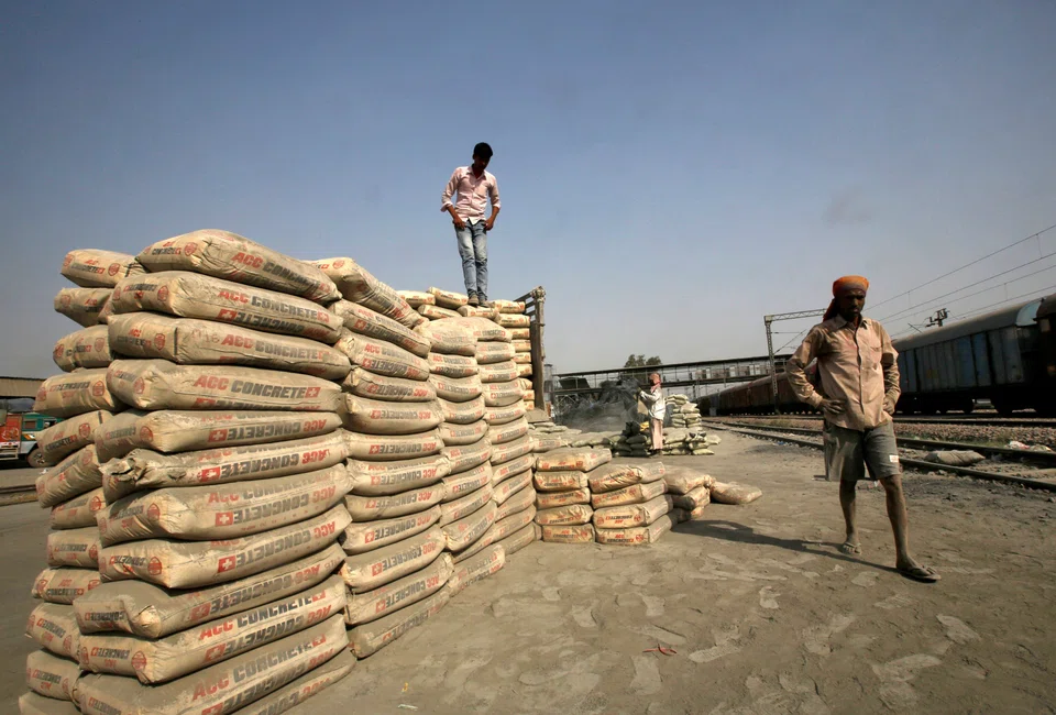 Labourers stand after unloading cement bags from a freight train in India. Holcim has been selling non-core cement businesses and buying new construction companies to benefit from rising demand for energy efficient buildings.