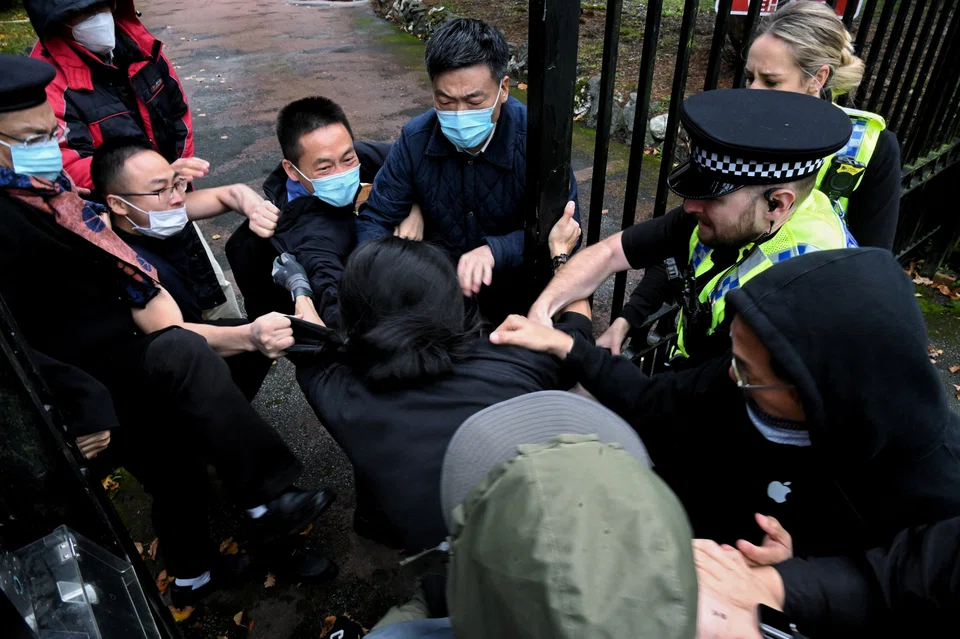 A man is pulled at the gate of the Chinese consulate in Manchester, Britain, after a demonstration against China's President Xi Jinping 