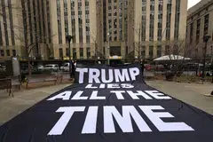 Anti-Trump protestors hold a banner in a park near the Manhattan Criminal Court in New York City, March 23, 2023. 