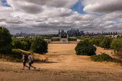 The parched grass in Greenwich Park in front of a view of skyscrapers in the Canary Wharf financial, business and shopping district of London last week. The unprecedented heat this summer has pushed plant life, infrastructure and residents to the edge. 