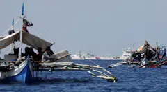 China Coast Guard vessels patrol past Philippine fishing boats at the disputed Scarborough Shoal that both China and the Philippines claim as their own.