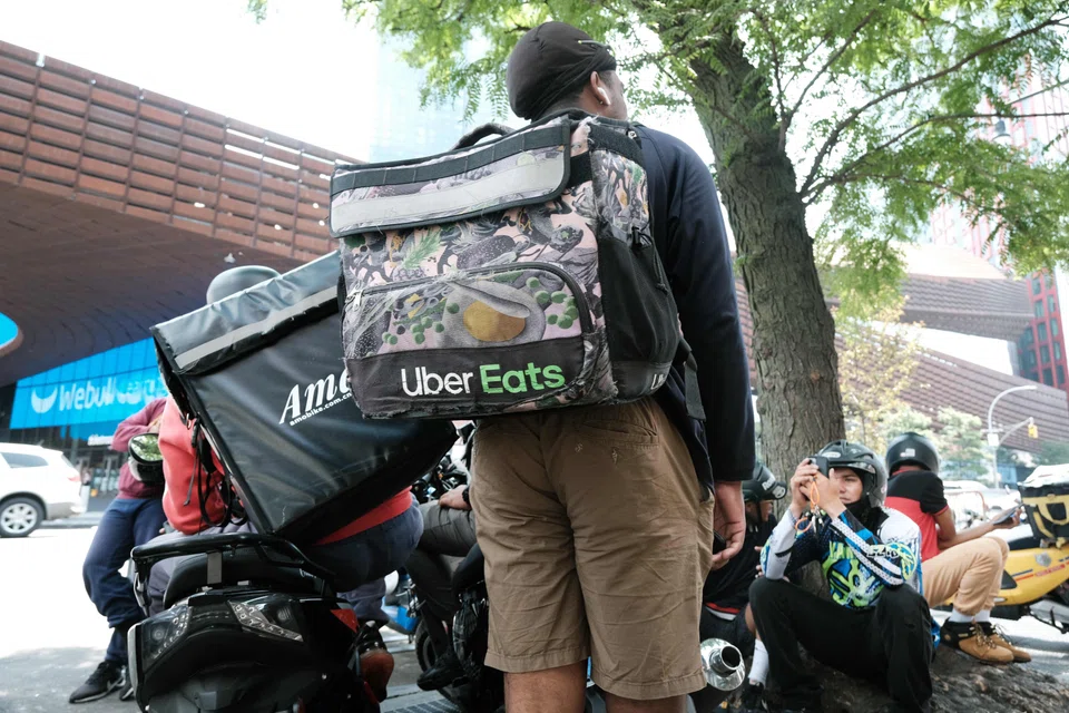 App-based delivery workers wait outside a restaurant in New York City, July 7, 2023.