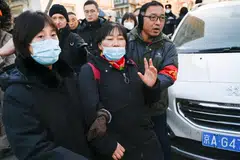 People are seen outside the court that began hearing compensation cases filed by the relatives of passengers of the missing Malaysia Airlines flight MH370, in Beijing on Nov 27, 2023. 
