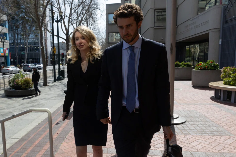 Theranos founder Elizabeth Holmes leaving a federal courthouse accompanied by her partner Billy Evans, after asking a US judge at a hearing to pause her prison sentence of more than 11 years while she urges an appeals court to review her conviction on charges of defrauding investors in her blood-testing startup.