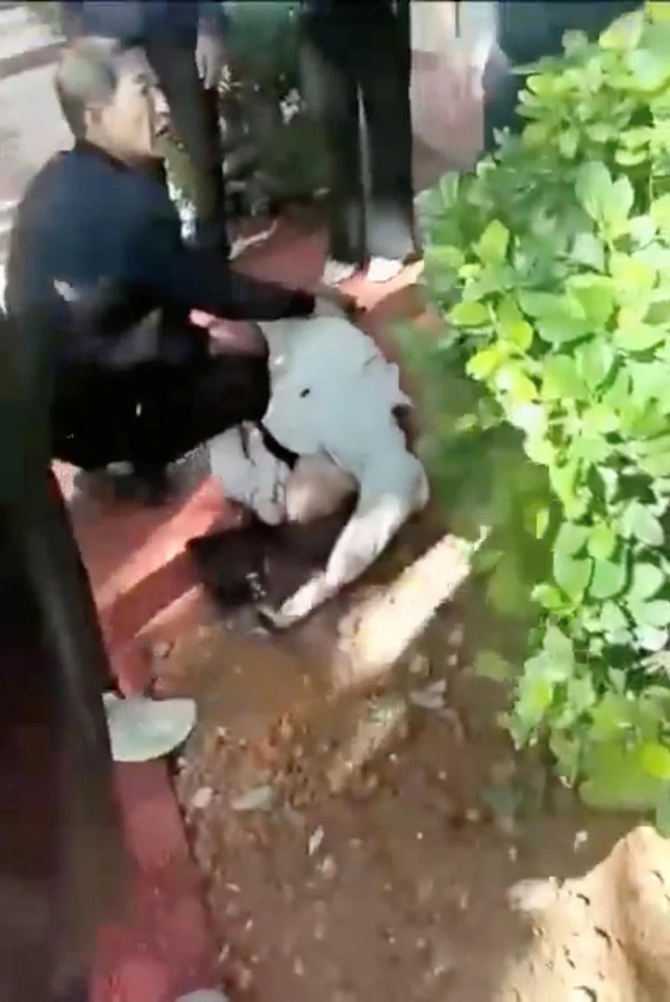 A man tends to a person lying on the ground following an explosion after artillery shells fell in Nansan, Yunnan province from Myanmar's Kokang region.