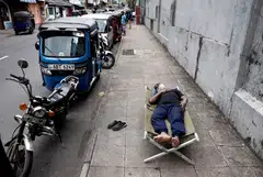A man sleeps on a folding bed on a pavement as he waits in queue to buy petrol due to fuel shortage, amid the country's economic crisis, in Colombo, Sri Lanka. 