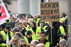 Lufthansa employees protest with a placard reading 'Also the ground is Lufthansa' outside Frankfurt Airport, Frankfurt, Germany on Feb 20, 2024.