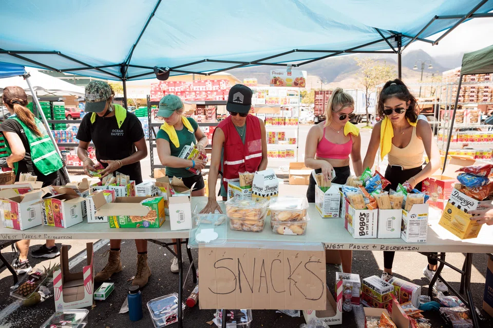 Volunteers sort through donated food items at an emergency aid distribution point for victims of last week's wildfire in Lahaina, on the Hawaiian island of Maui.