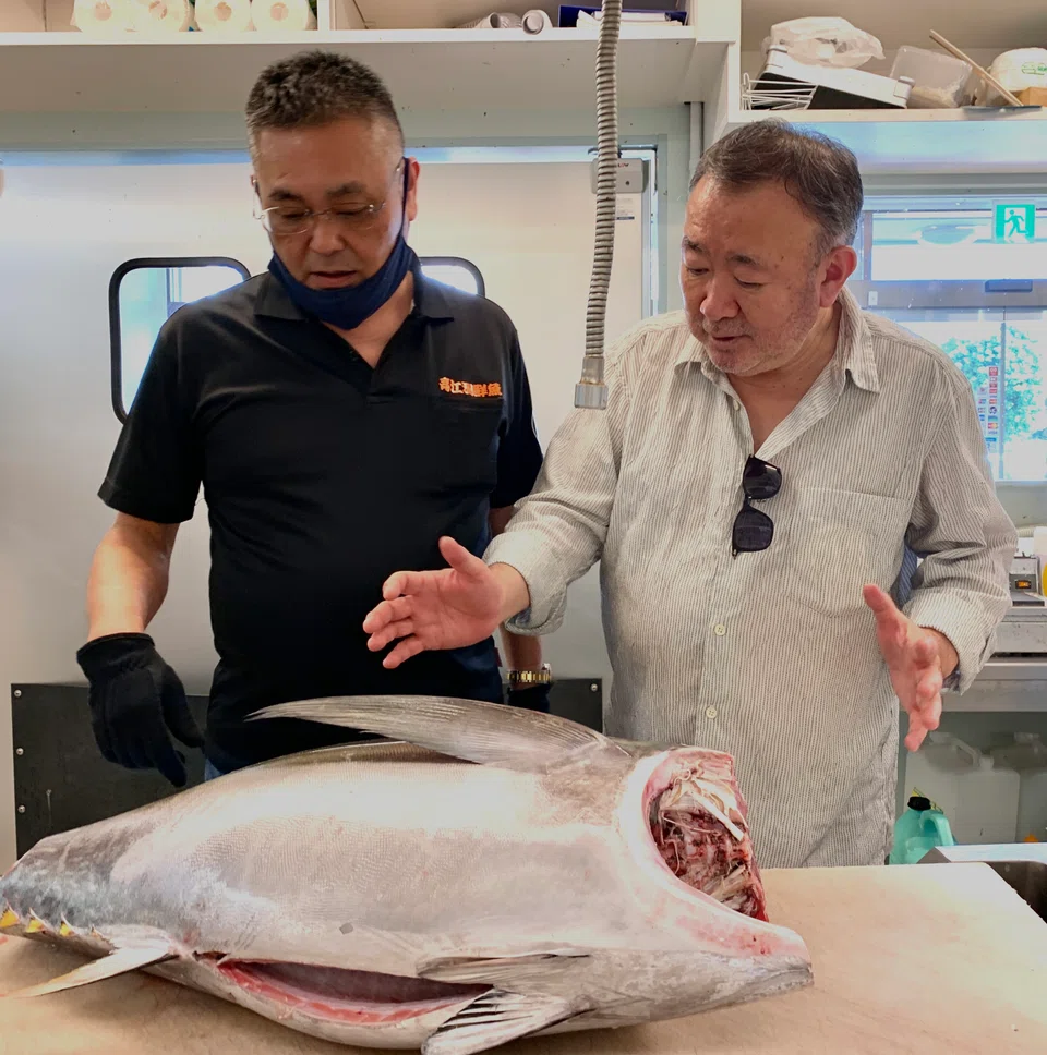 Wakuda sizes up a big-eye tuna with fish supplier Kaoru Takaesu,