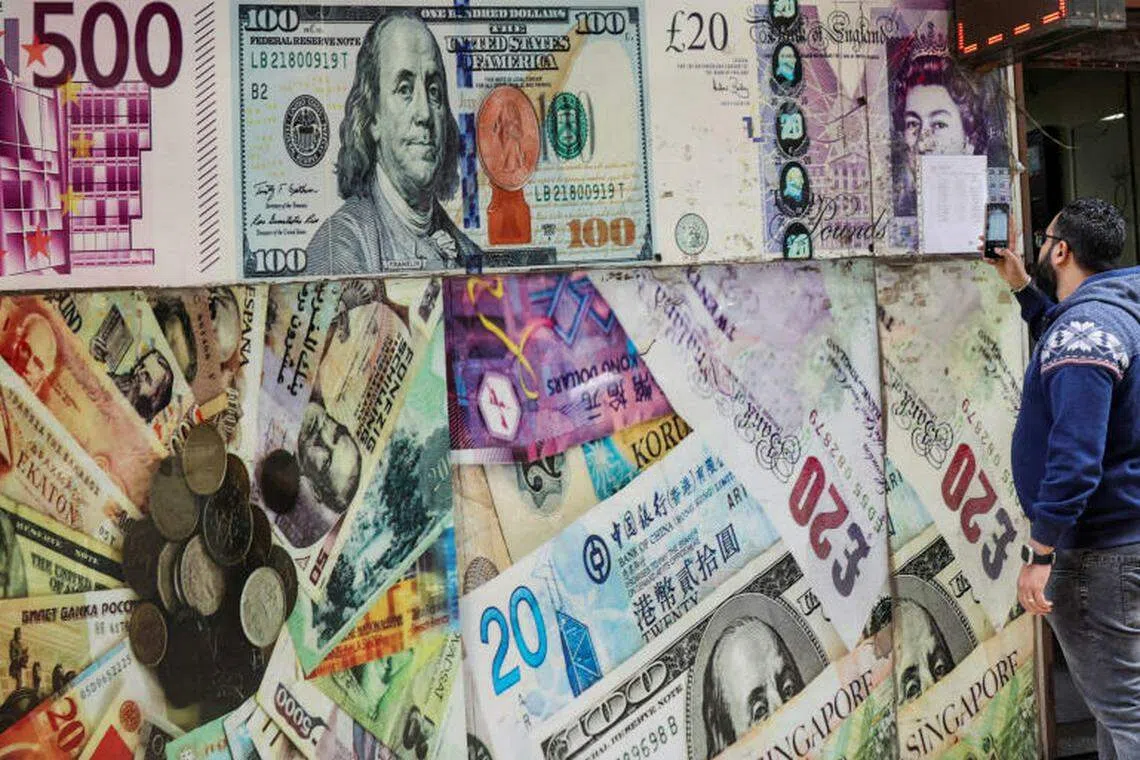 A man takes a photograph of exchange rates at a money changer. 