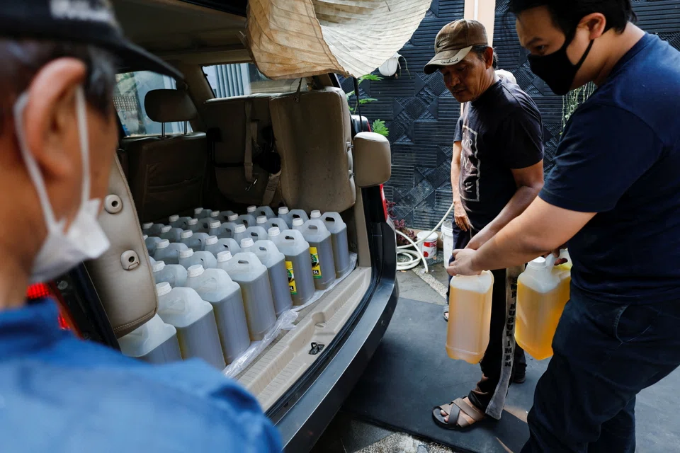 Residents prepare containers of cooking oil to be distributed to locals at a filling station after stocks ran out in Jakarta. 