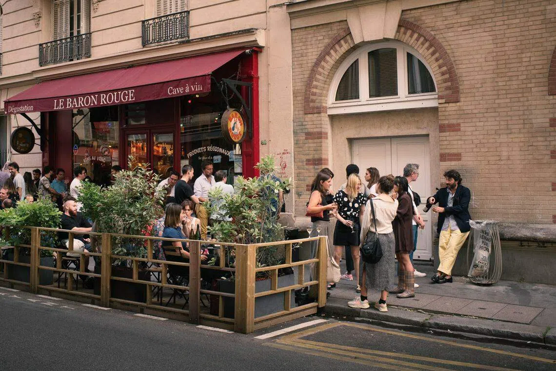 Patrons outside Le Baron Rouge, near Place d'Aligre, in the Bastille district of Paris, Aug 10, 2023. Mayor Anne Hidalgo signed a decree in 2021 that allows open-air terraces to return every year from April through November. 