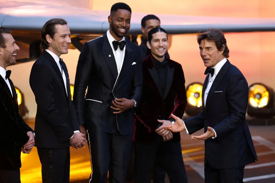 FILE PHOTO: US actor Tom Cruise (extreme right) with some members of the cast of Top Gun: Maverick at the premiere of the film in London on May 19. The family of the (now late) writer of the 1983 article "Top Guns" is suing for unspecified damages, including some profits from the film. The family holds the copyright to the article which inspired the movie and its derivative sequel. 
