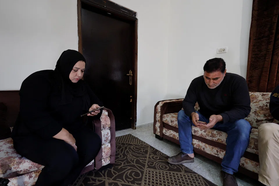 Members of the Abu Maria family watch the news in their house, as they wait for their teenage son's possible release from Israeli prison as part of the Israel-Hamas prisoner swap.