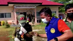 Officials and authorities guard the gate of a daycare centre as people wait, after a mass shooting, in Uthai Sawan, Nong Bua Lamphu Province, Thailand.
