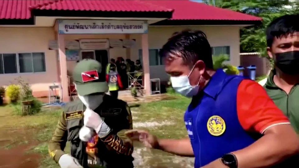 Officials and authorities guard the gate of a daycare centre as people wait, after a mass shooting, in Uthai Sawan, Nong Bua Lamphu Province, Thailand.