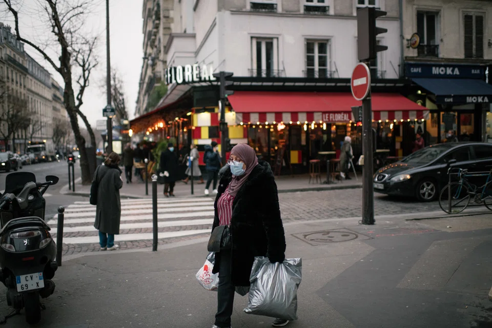 A woman walks near the Goncourt metro station in Paris on Jan 25, 2022. Both President Emmanuel Macron and challenger Marine Le Pen threw themselves into a final flurry of campaigning Friday, firing off attacks in interviews before last-minute walkabouts and rallies.