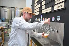 A worker pours a pint of beer at Pressure Drop Brewery, in north London; Pressure Drop is hoping the experiment will not only improve their employees’ productivity but also their well-being. At the same time, it will reduce their carbon footprint.