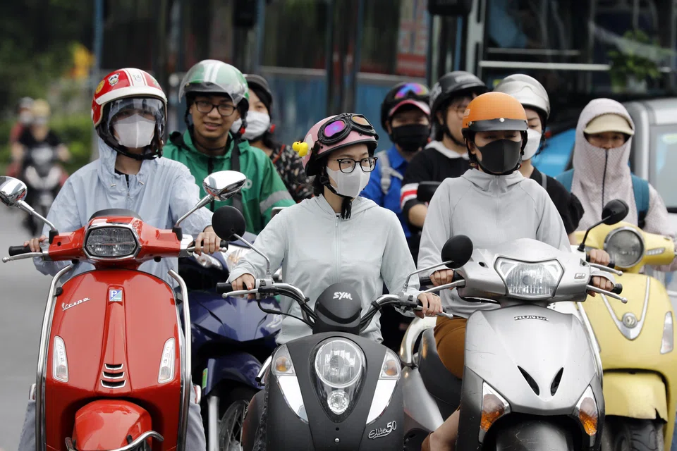 People wearing long clothing to protect themselves from the heat while riding motorcycles along a street in Hanoi. Extreme weather conditions in Vietnam saw temperatures exceed 44 deg C in some regions recently.