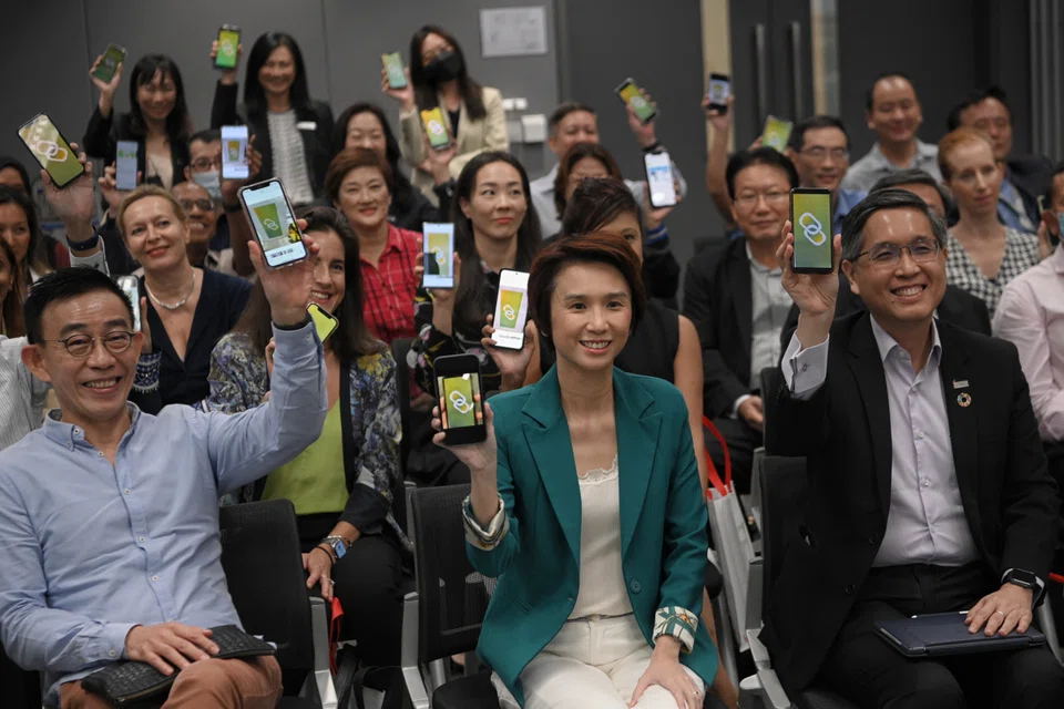Minister of State for Trade and Industry, and Culture, Community and Youth Low Yen Ling (foreground centre) and Singapore Business Federation (SBF) chief executive officer Lam Yi Young (foreground right), hold their phones up with the OneTAC SG app and pose for pictures with guests after launch of the OneTAC SG platform at the SBF centre.